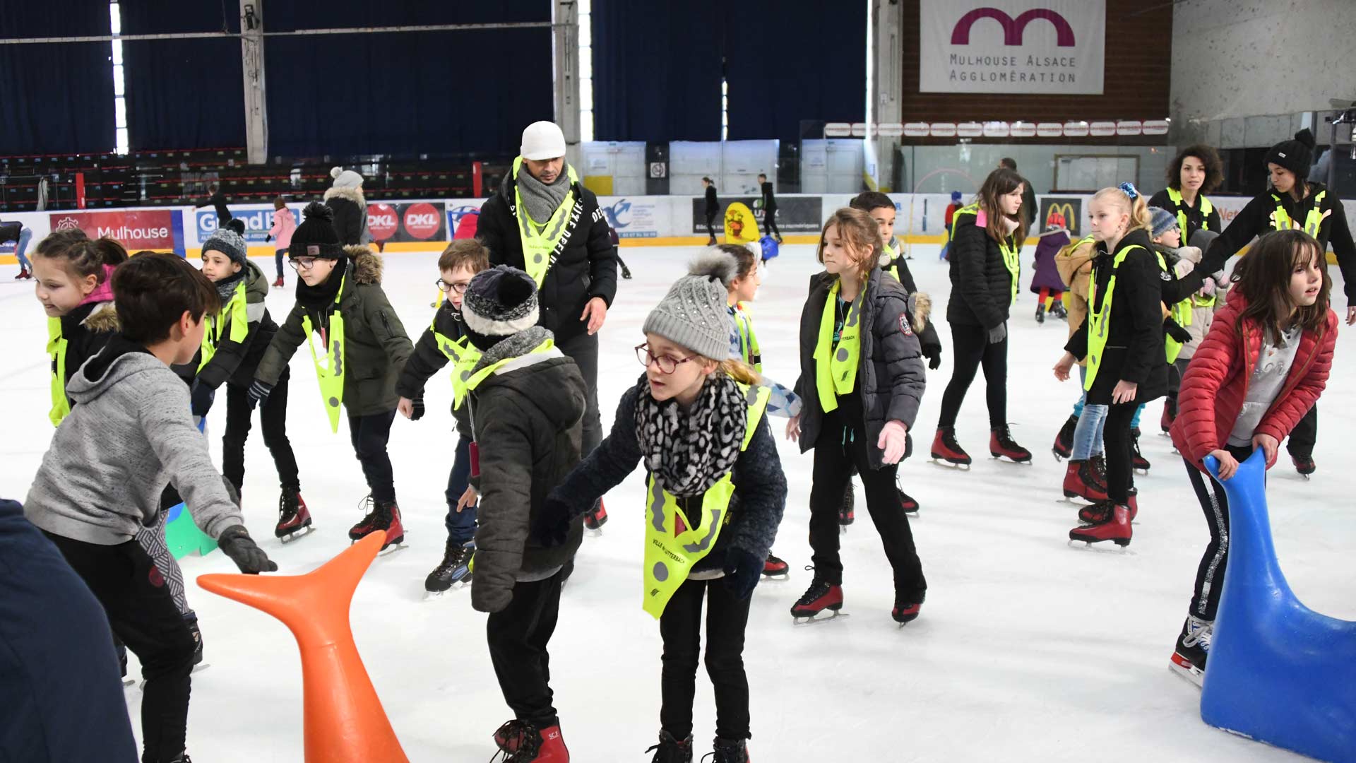 Un groupe d'enfants avec des filets jaunes sur la Patinoire Olympique de Mulhouse